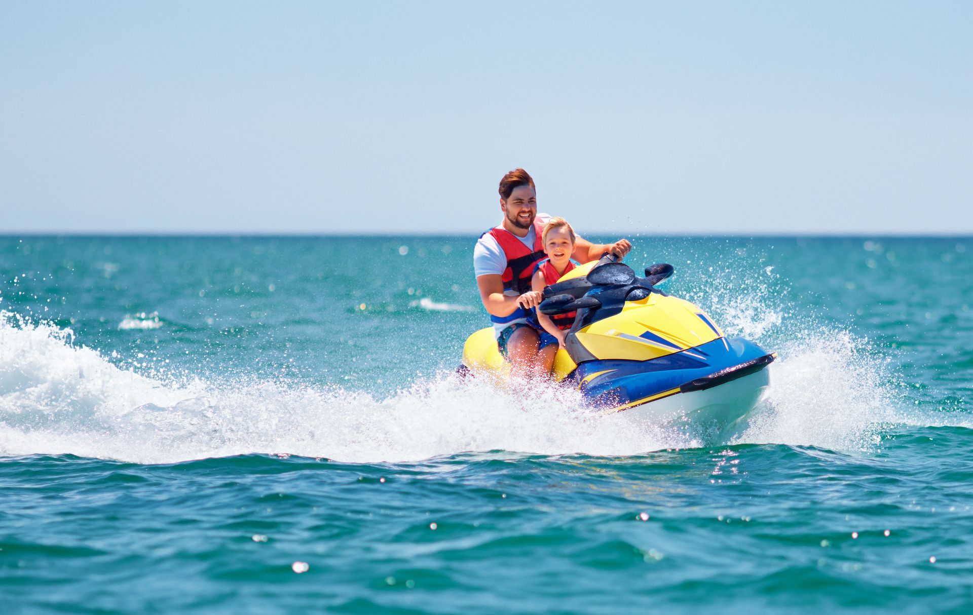 happy, excited family, father and son having fun on jet ski at summer vacation