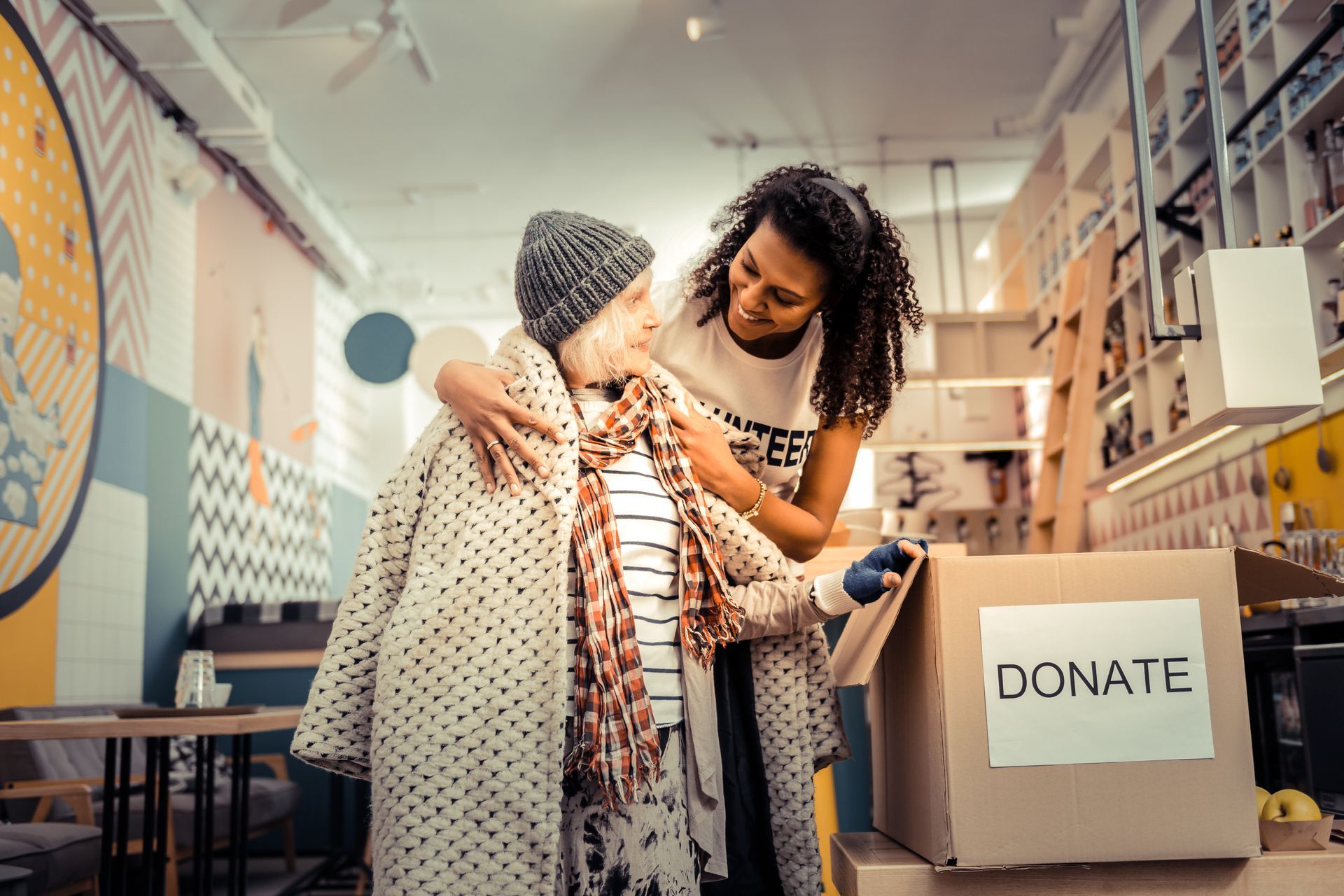 You need it. Nice joyful woman smiling while giving her old coat to a pleasant aged woman