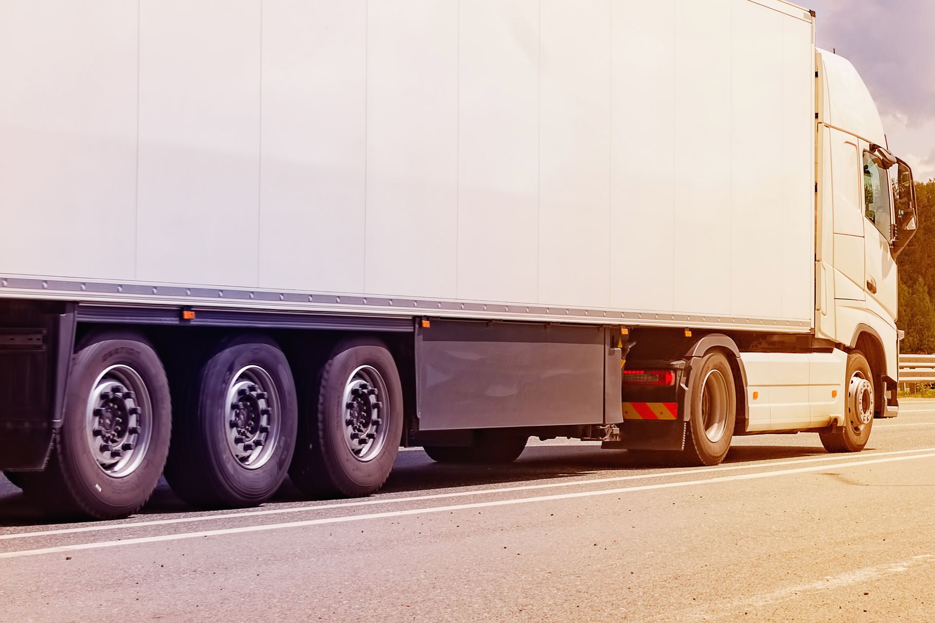 Close-up of a heavy-duty car with a semitrailer drives on a motorway on a summer day. Transport logistics for the delivery of goods.