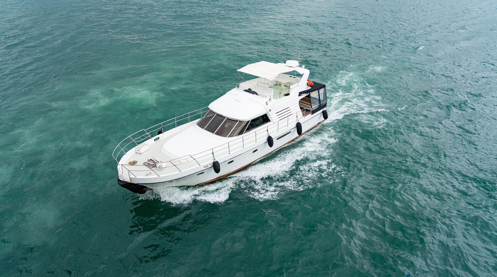 A small white yacht sails on the sea top view