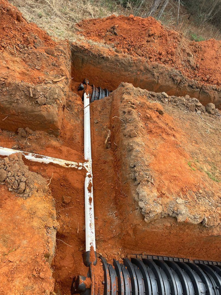 Heavy Duty Pumping | A pipe is being installed in the dirt next to a septic tank.