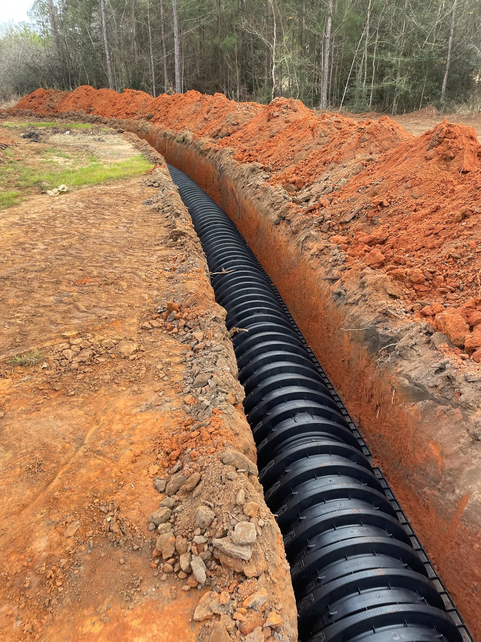 Heavy Duty Pumping | A large black pipe is being installed in the dirt.
