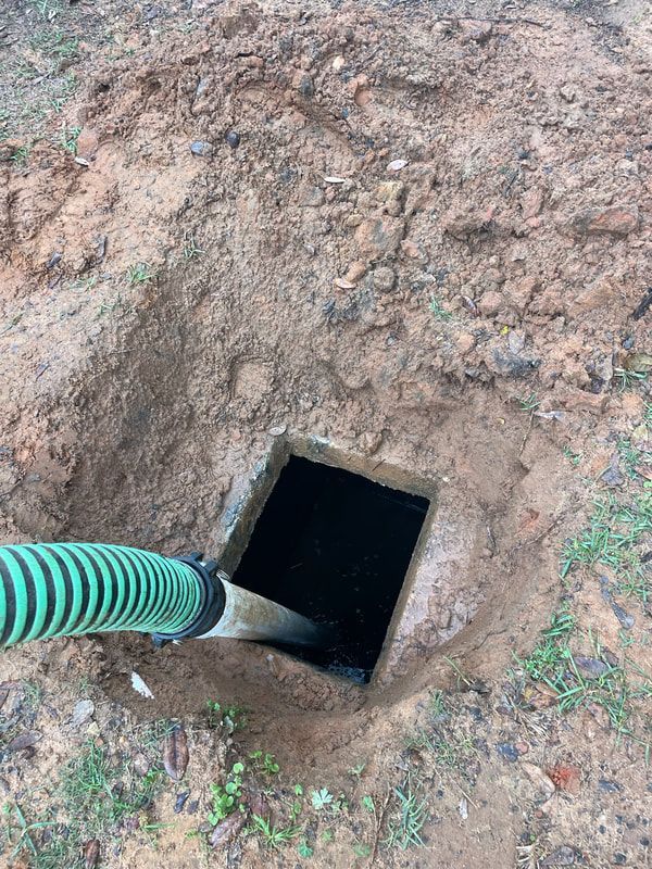 Heavy Duty Pumping | A green hose is being used to pump water into a septic tank.