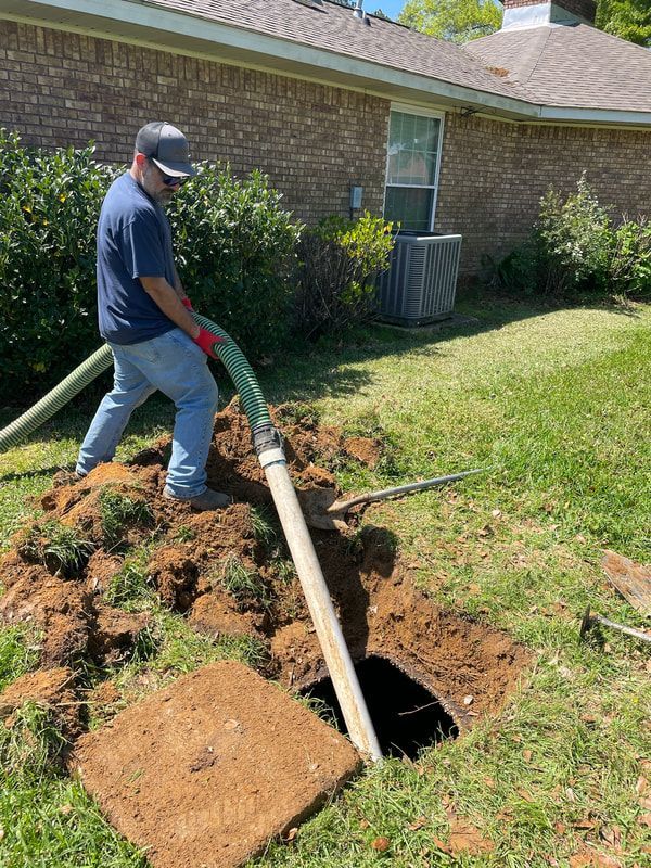 Heavy Duty Pumping | A man is pumping water into a hole in the ground in front of a house.