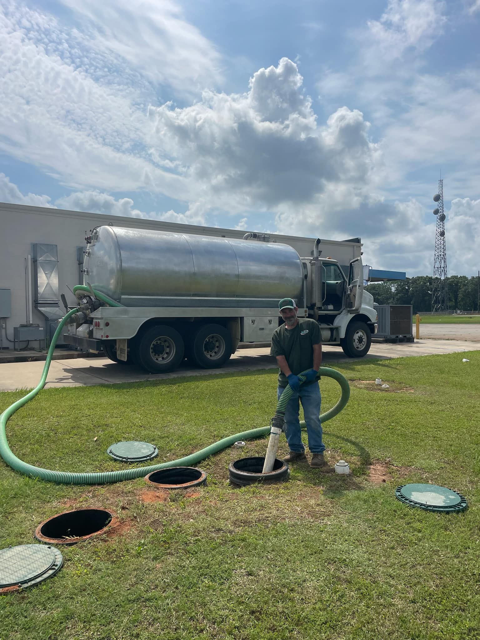 Heavy Duty Pumping | A man is pumping septic tanks with a truck in the background.