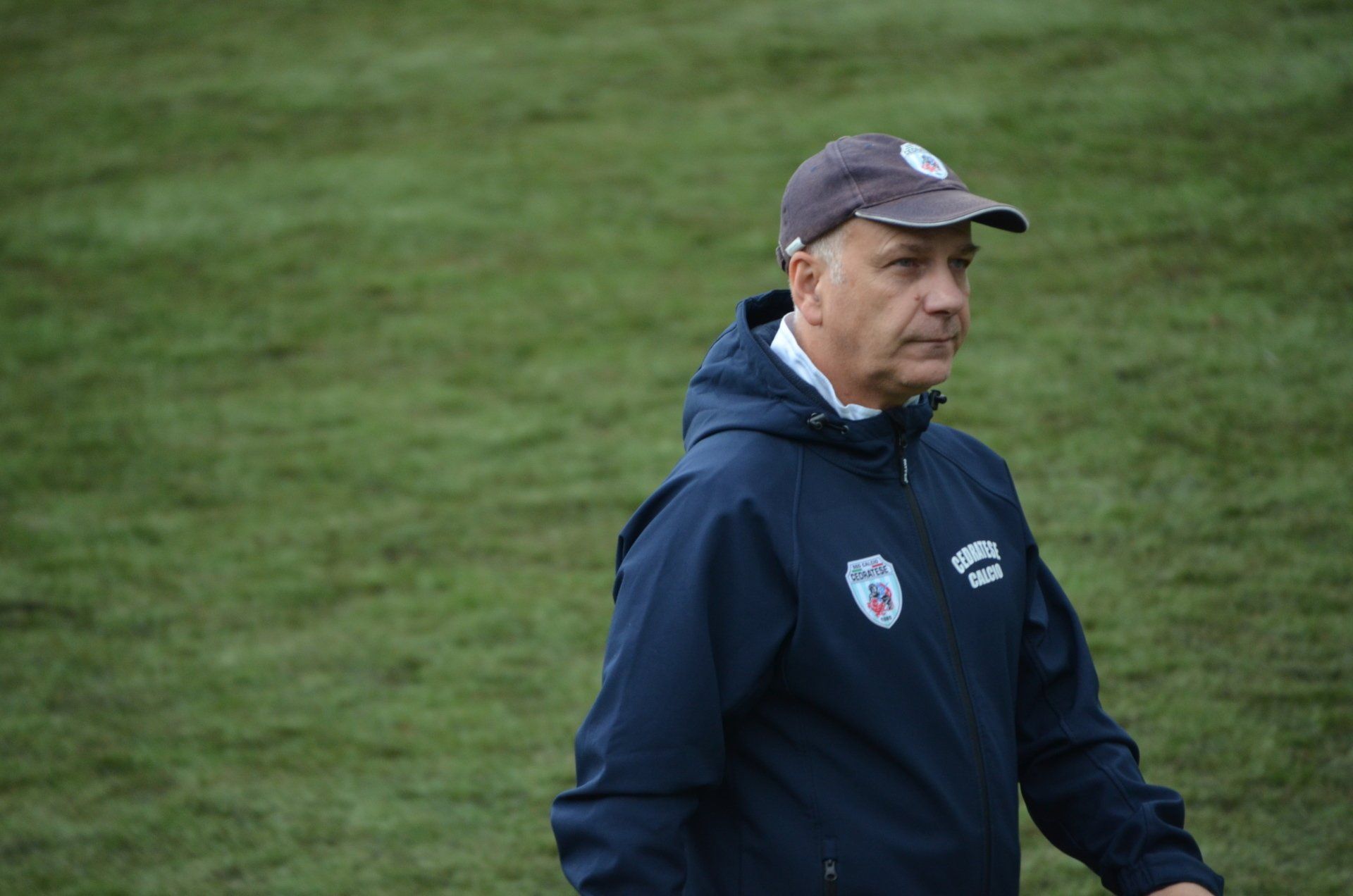 un uomo che indossa un cappello e una giacca è in piedi su un campo.