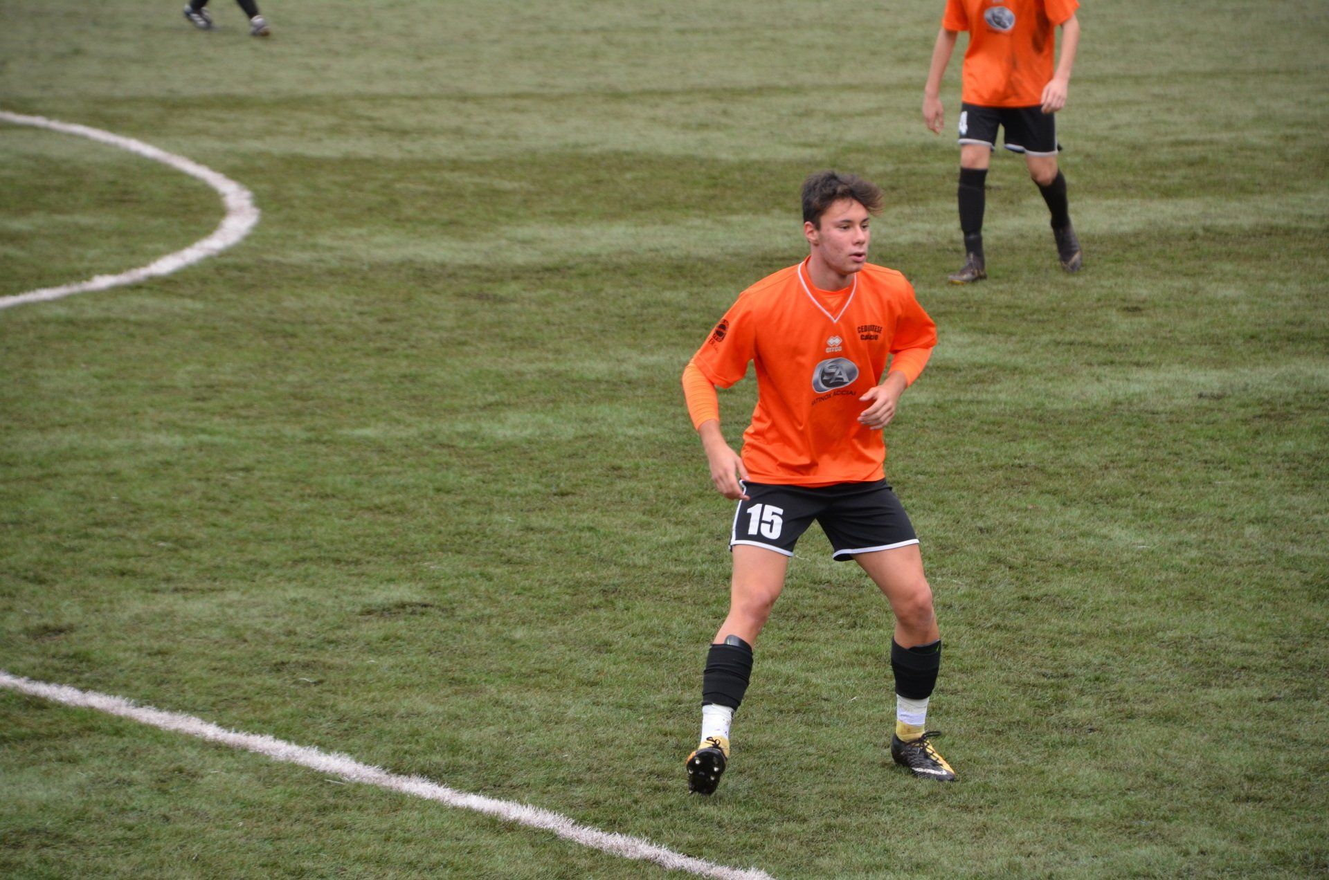 un calciatore con il numero 15 sui pantaloncini è in piedi in un campo.