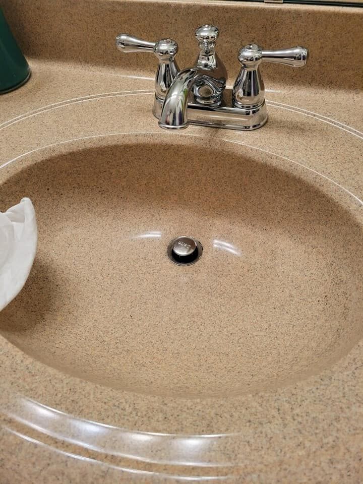 Tan bathroom sink with chrome faucet; white paper on the left.
