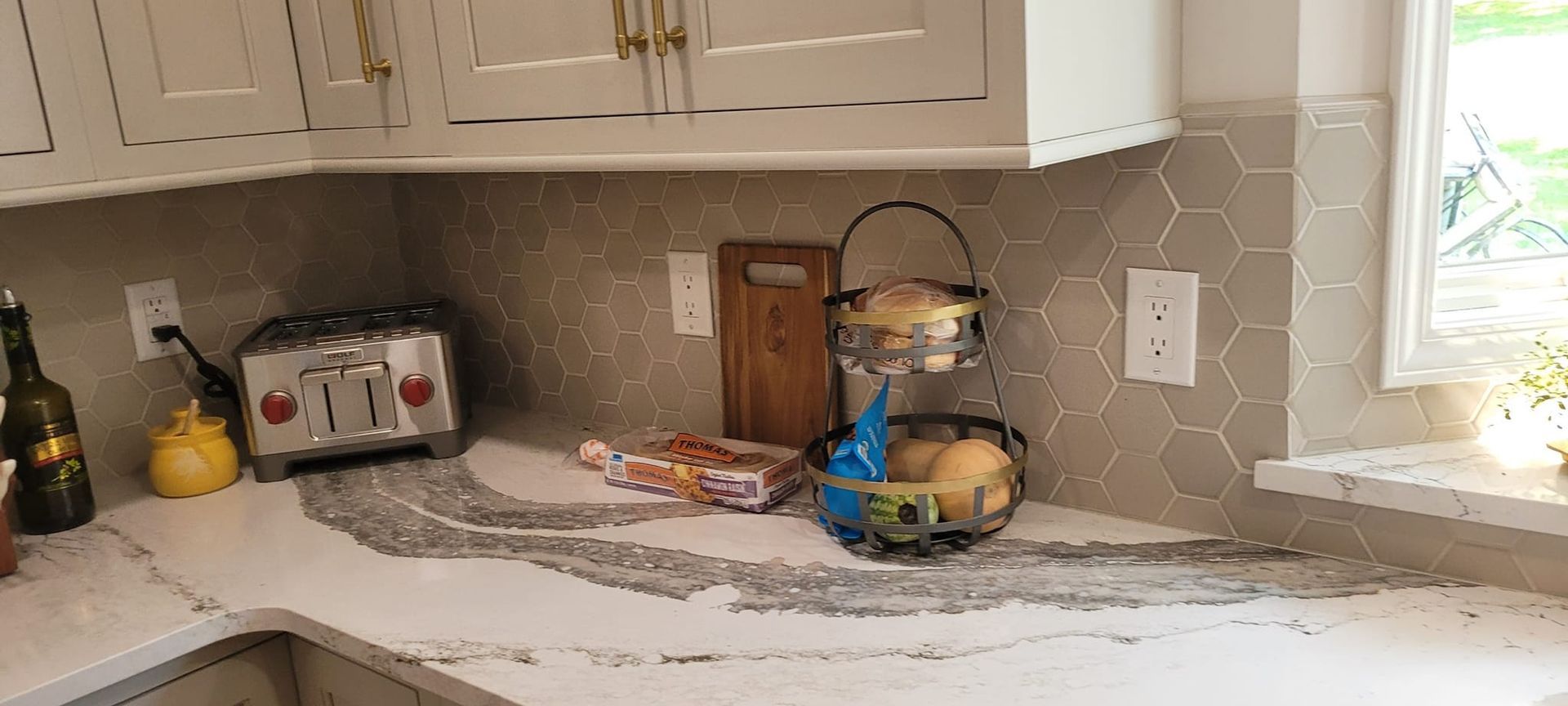 A kitchen counter with a toaster, fruit basket, and cutting board.