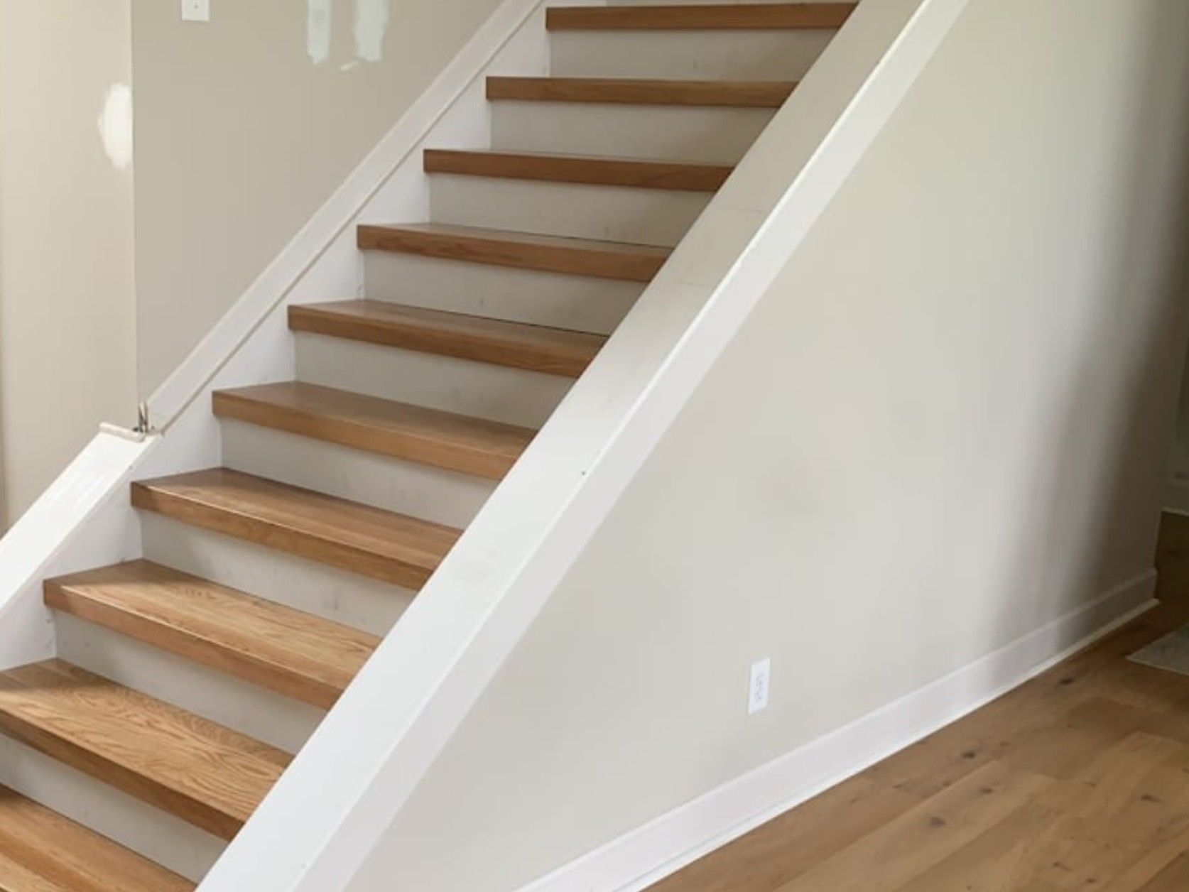 Wooden staircase with white trim and beige walls.
