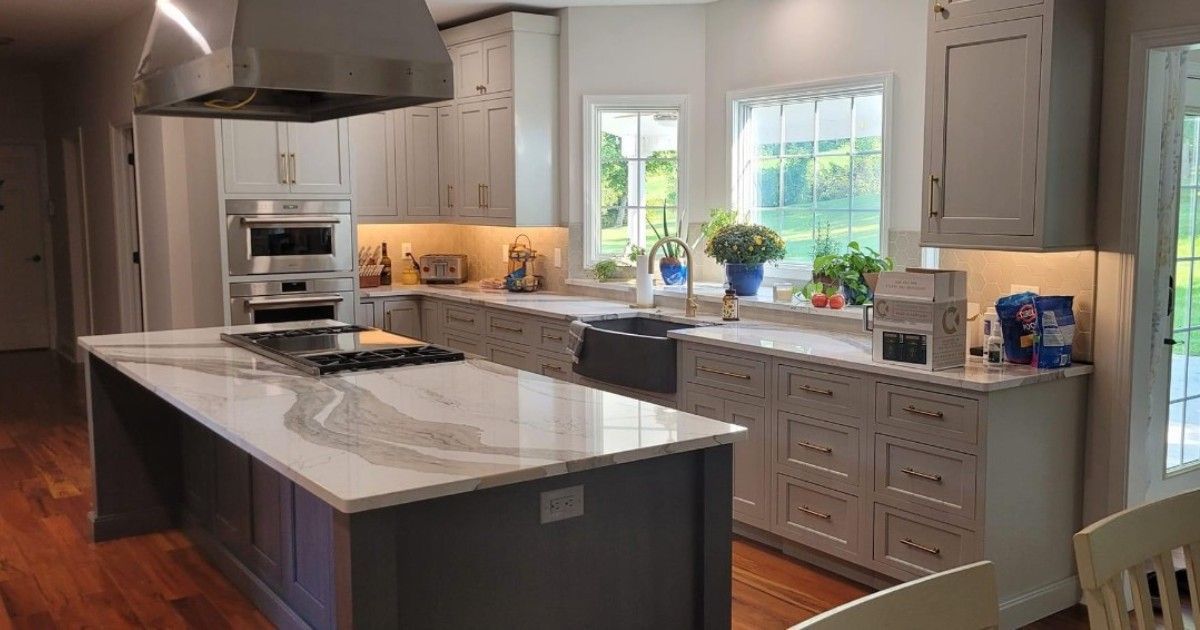 Modern kitchen with gray cabinets, white countertops, and an island with a cooktop.