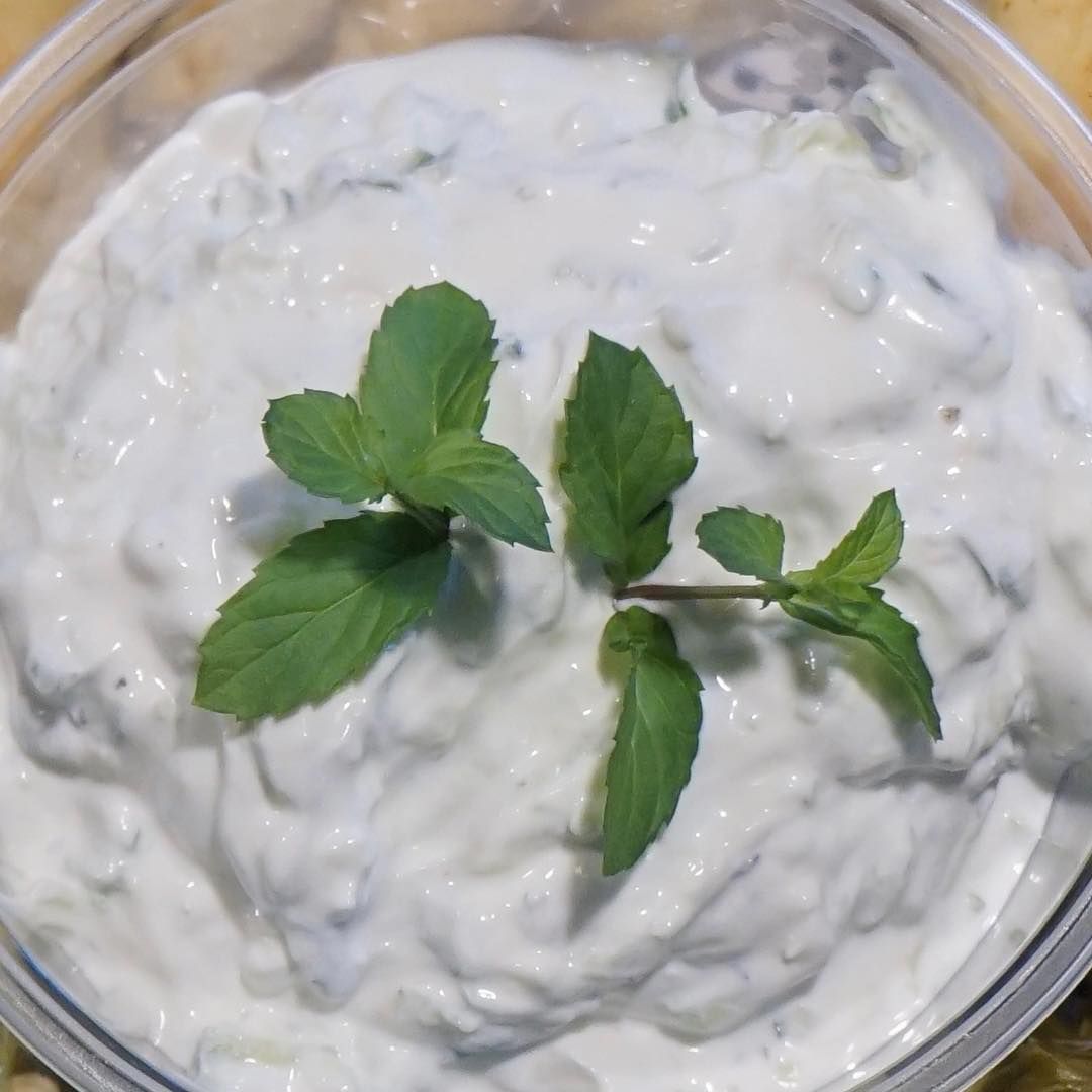 A bowl of white dip with mint leaves on top