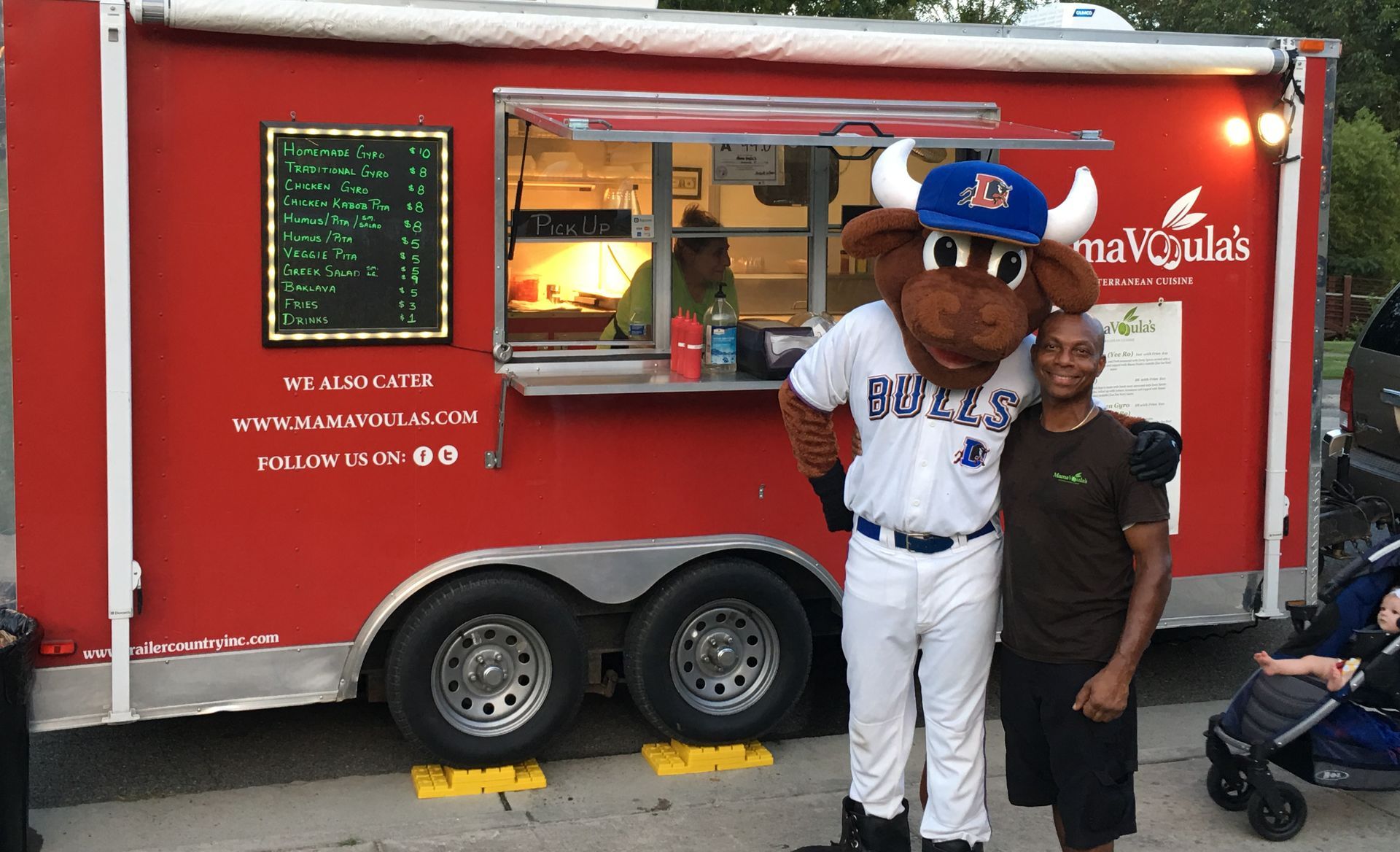 A man and a mascot are standing in front of a food truck