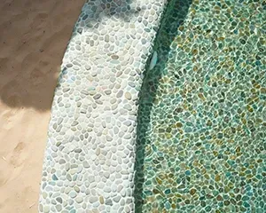 Piscina revestida com seixos. Areia da praia à esquerda.