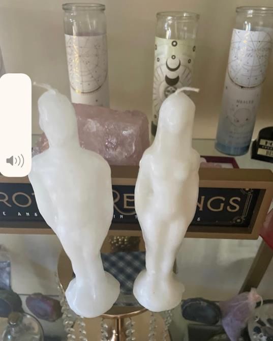 Two white candles are sitting on a table next to a sign that says rings
