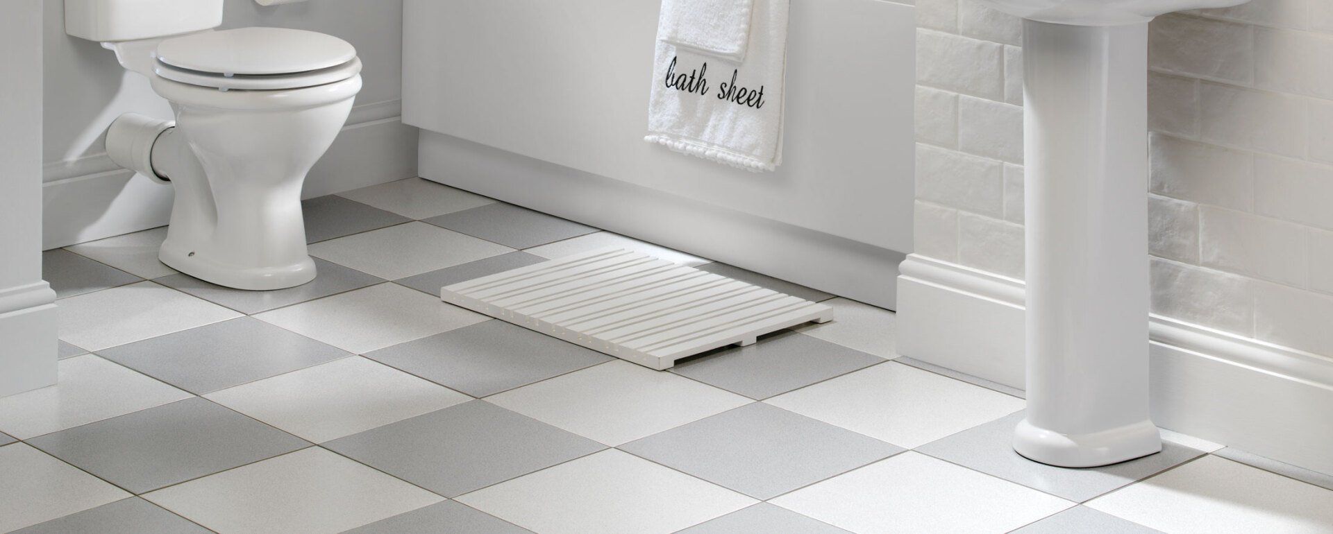 A bathroom with a toilet , sink , and checkered floor.