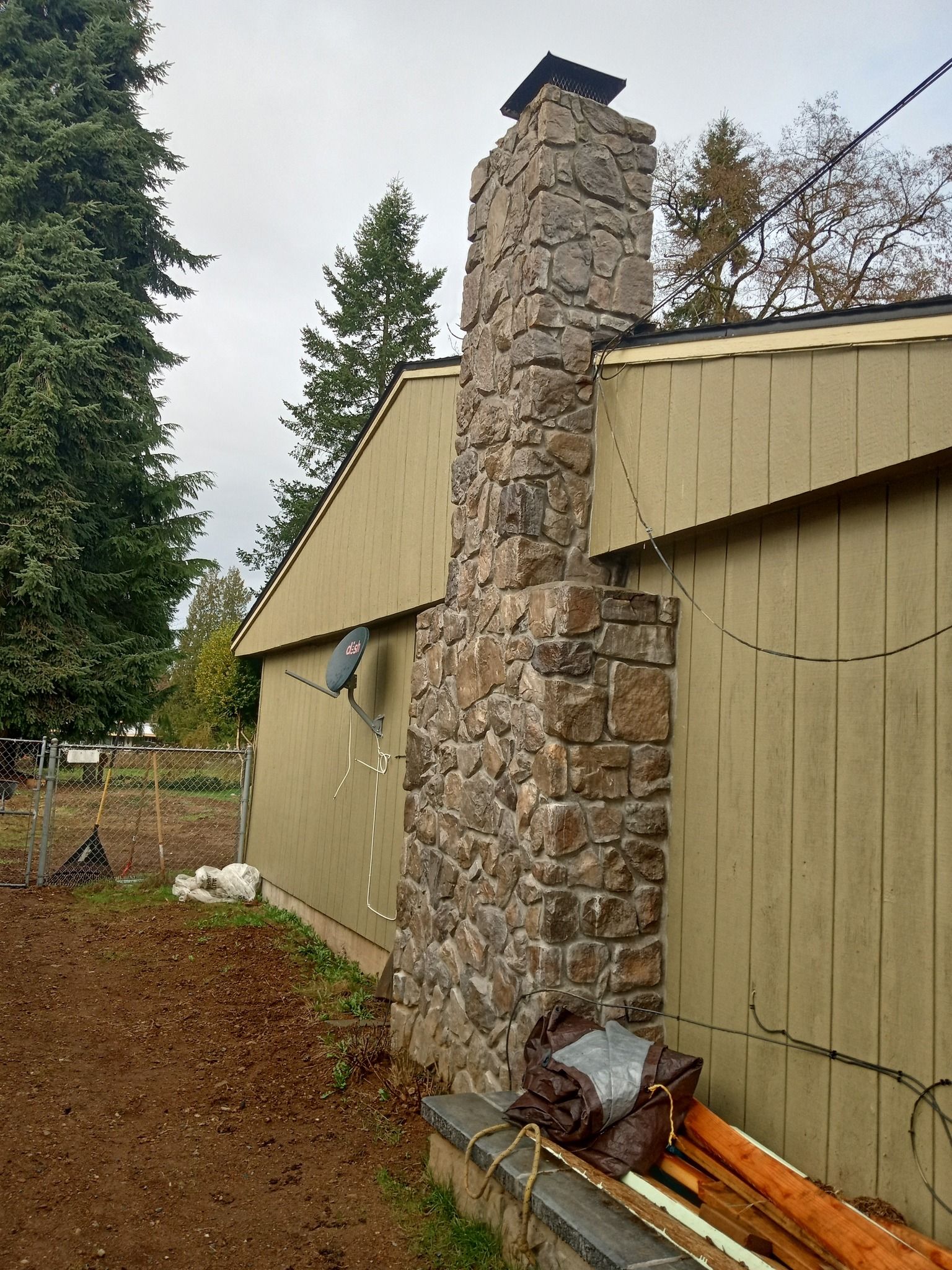 A large stone chimney is sitting on the side of a house.