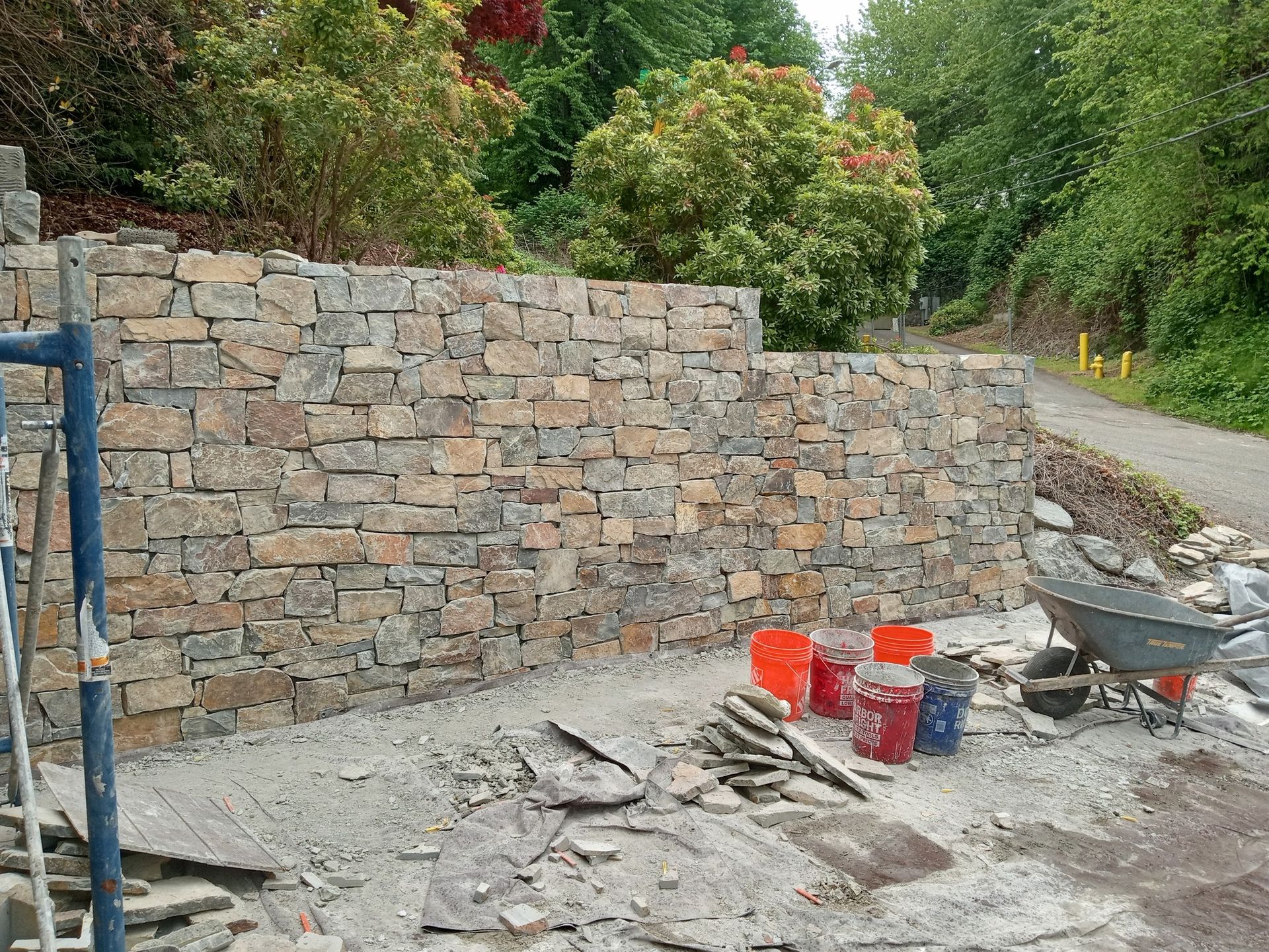 A stone wall is being built on the side of a road.