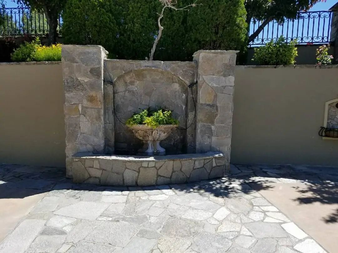 A stone wall with a fountain in the middle of it.