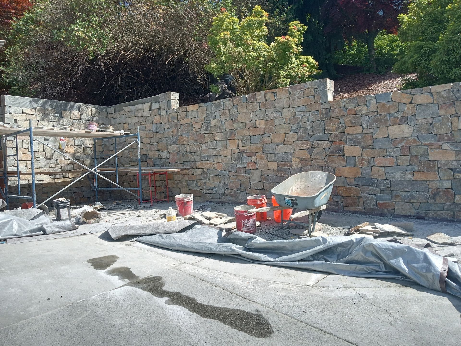 A wheelbarrow is sitting in front of a stone wall.