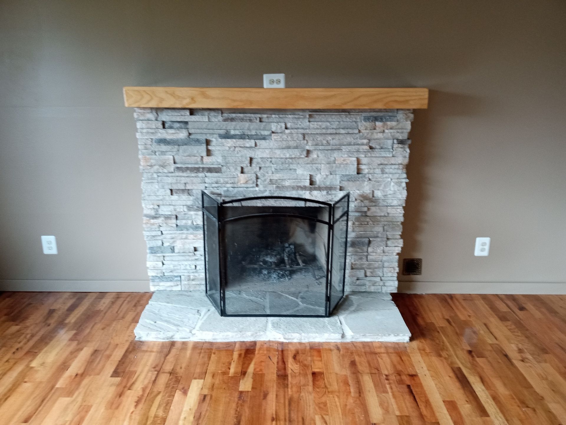 A fireplace with a screen and a wooden mantle