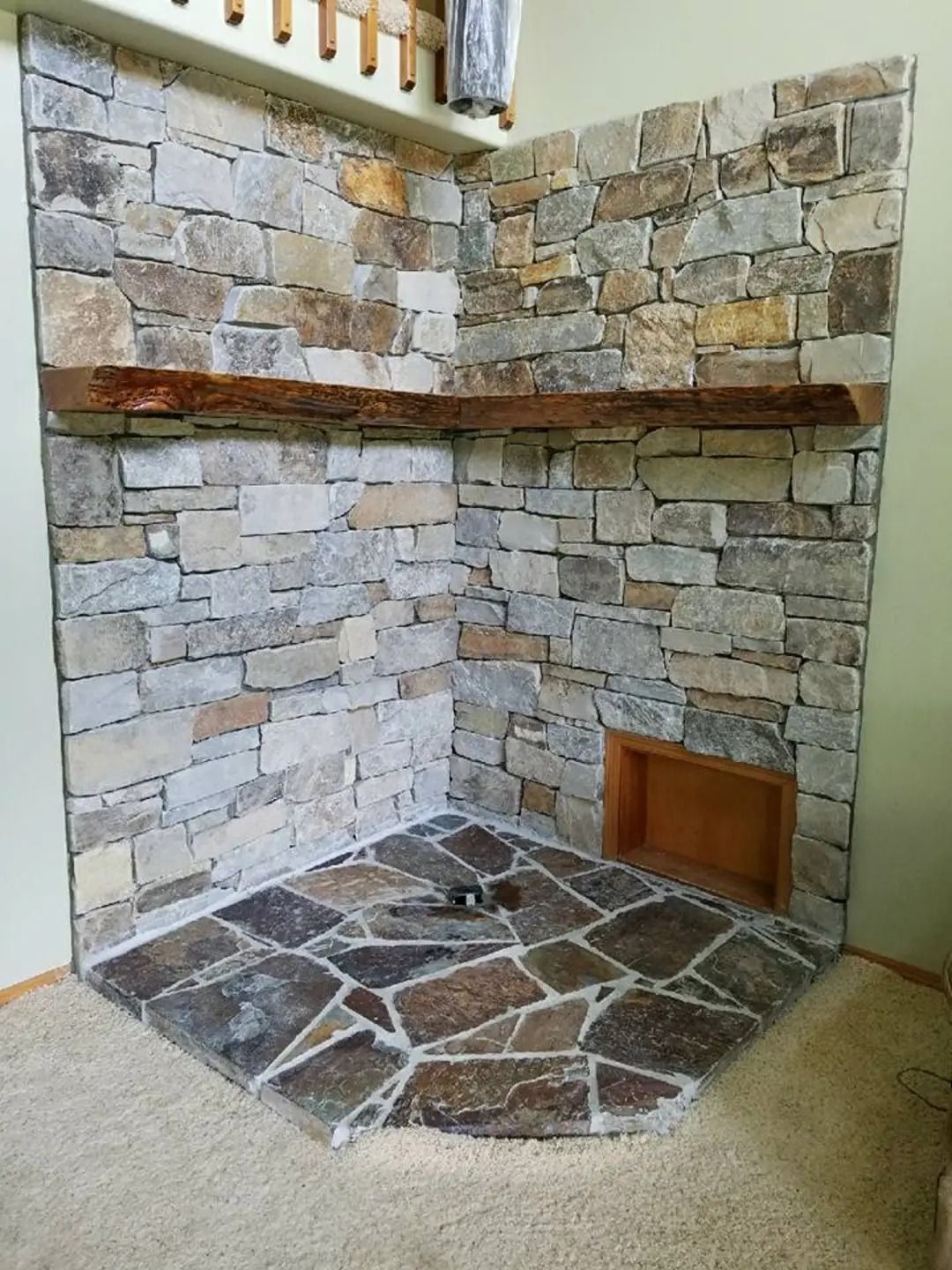A stone fireplace with a wooden mantle in a living room.