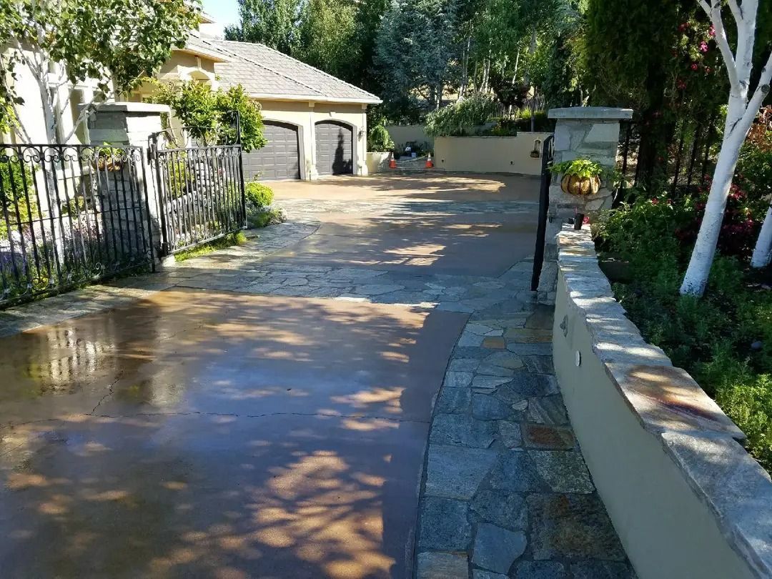 A driveway leading to a house with a fence and trees.
