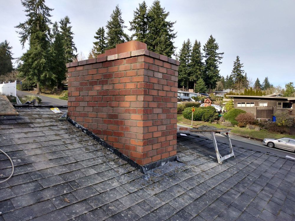 A brick chimney is sitting on top of a roof.