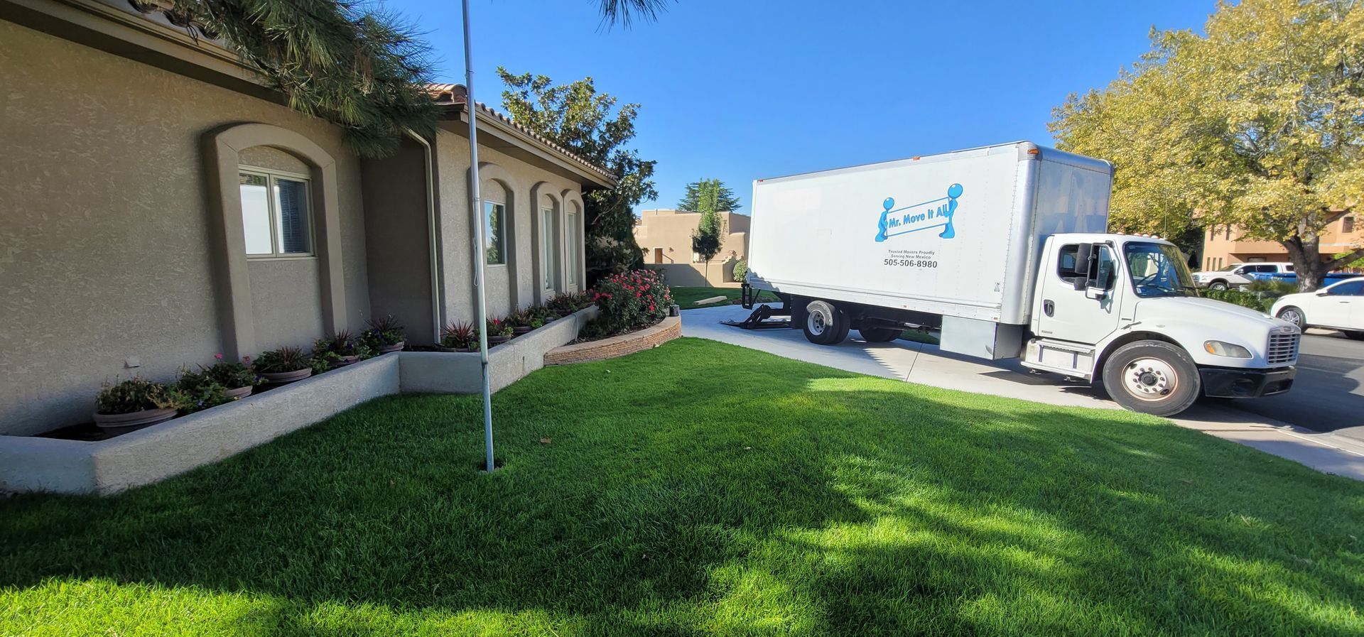 A white moving truck is parked on the side of the road.