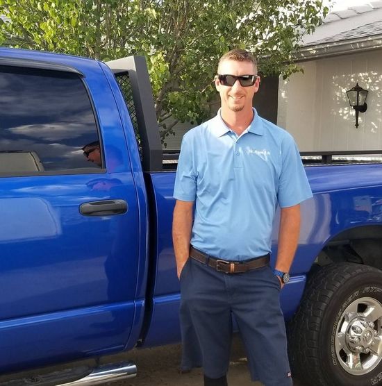 A man wearing sunglasses is standing in front of a blue truck