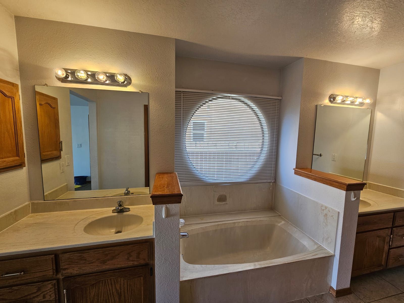 A bathroom with two sinks , a tub and a mirror.