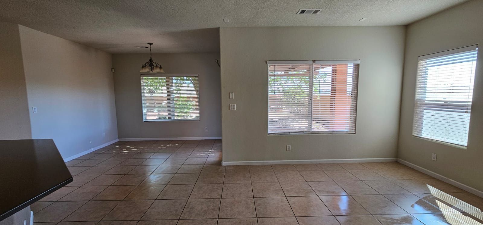 An empty living room with a lot of windows and tile floors