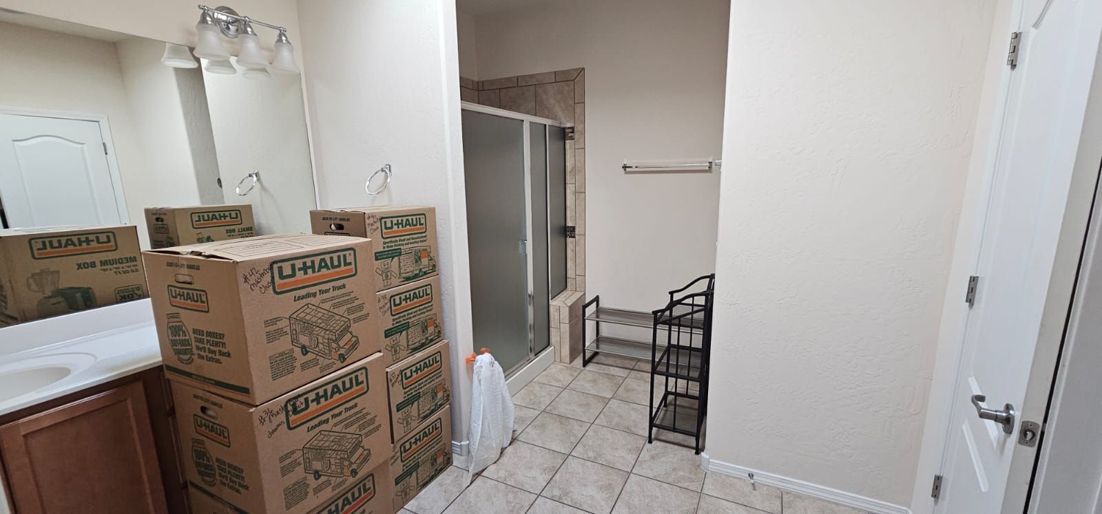 A bathroom with boxes stacked on top of each other and a shower.