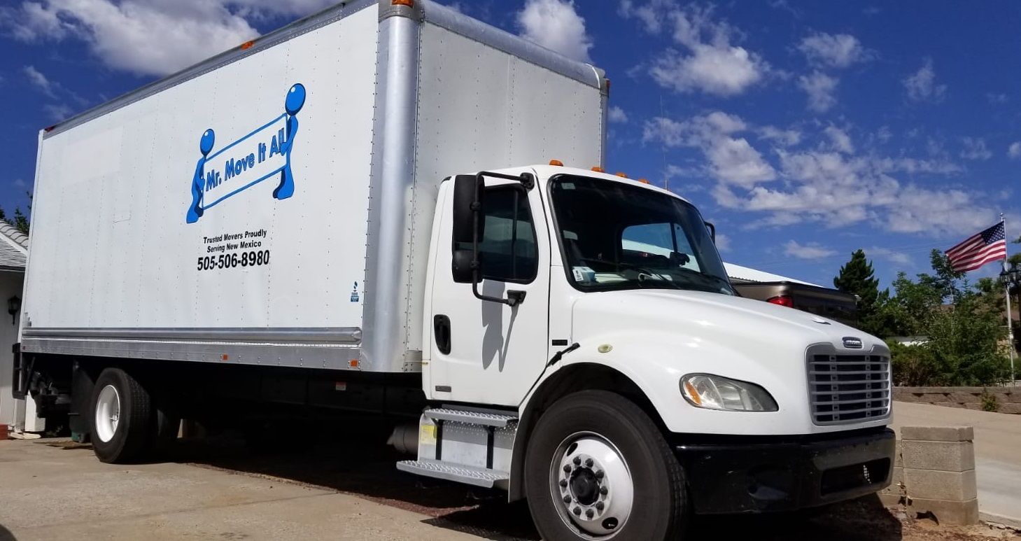 A white truck with a blue logo on the side is parked in a parking lot.