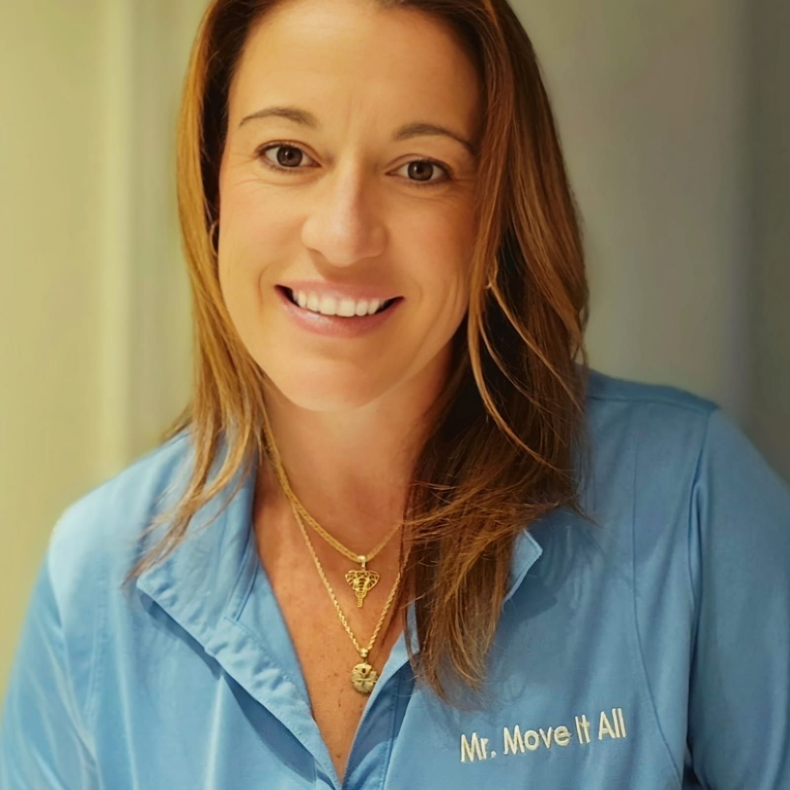 A woman in a blue shirt is holding a clipboard in front of cardboard boxes.