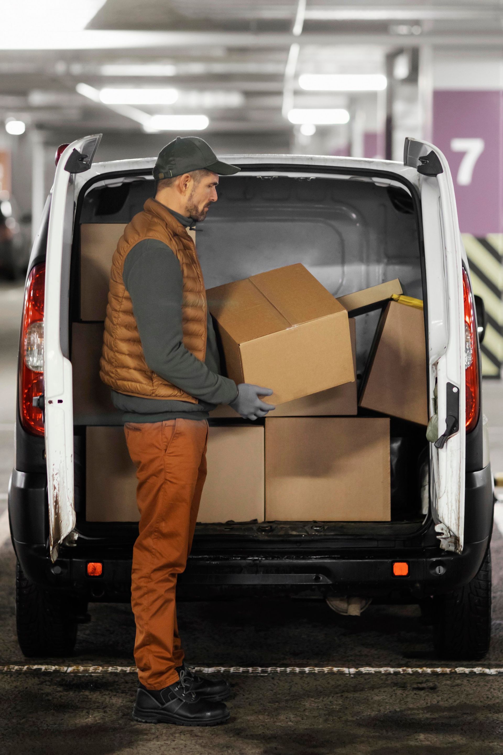 A delivery man is loading boxes into the back of a van.