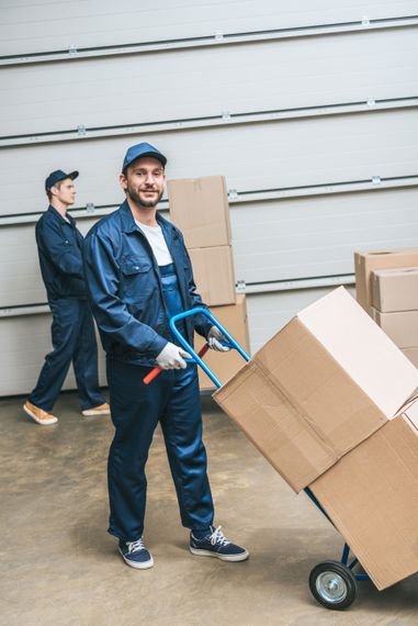 A man is pushing a cart with boxes on it in a warehouse.