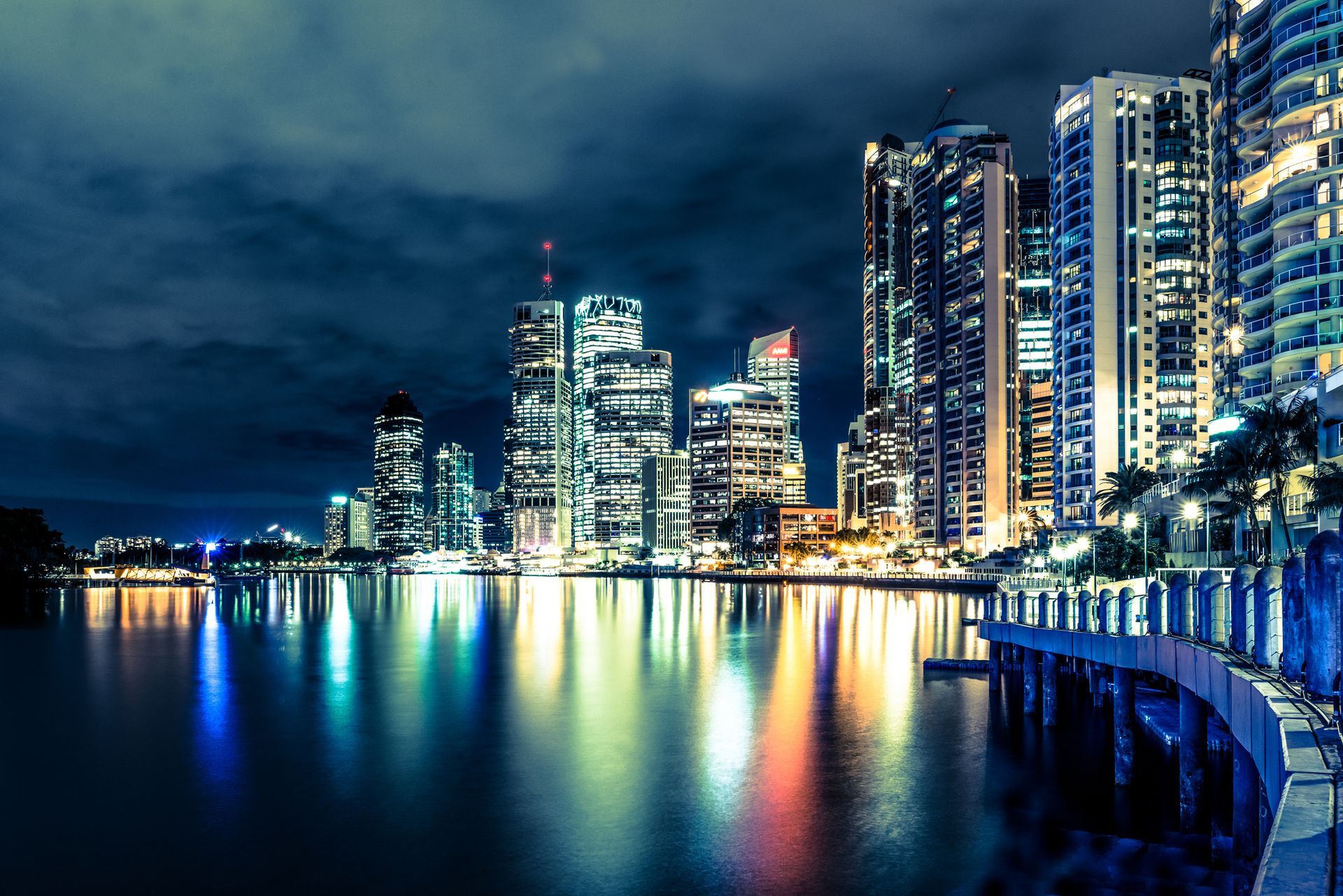 A city skyline at night with a body of water in the foreground.