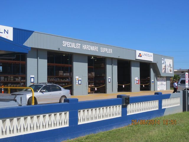 A car is parked in front of a building that says specialist hardware supplier