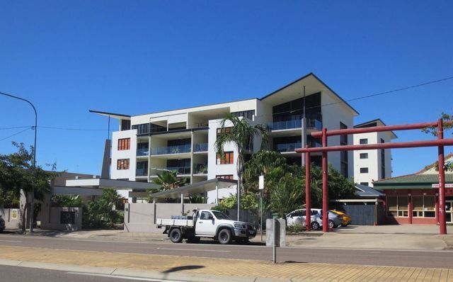 A white truck is parked in front of a large building