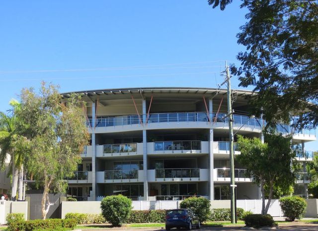 A large apartment building with a blue car parked in front of it