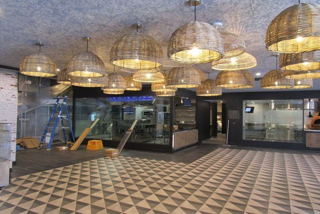 A large room with lots of wicker lamps hanging from the ceiling