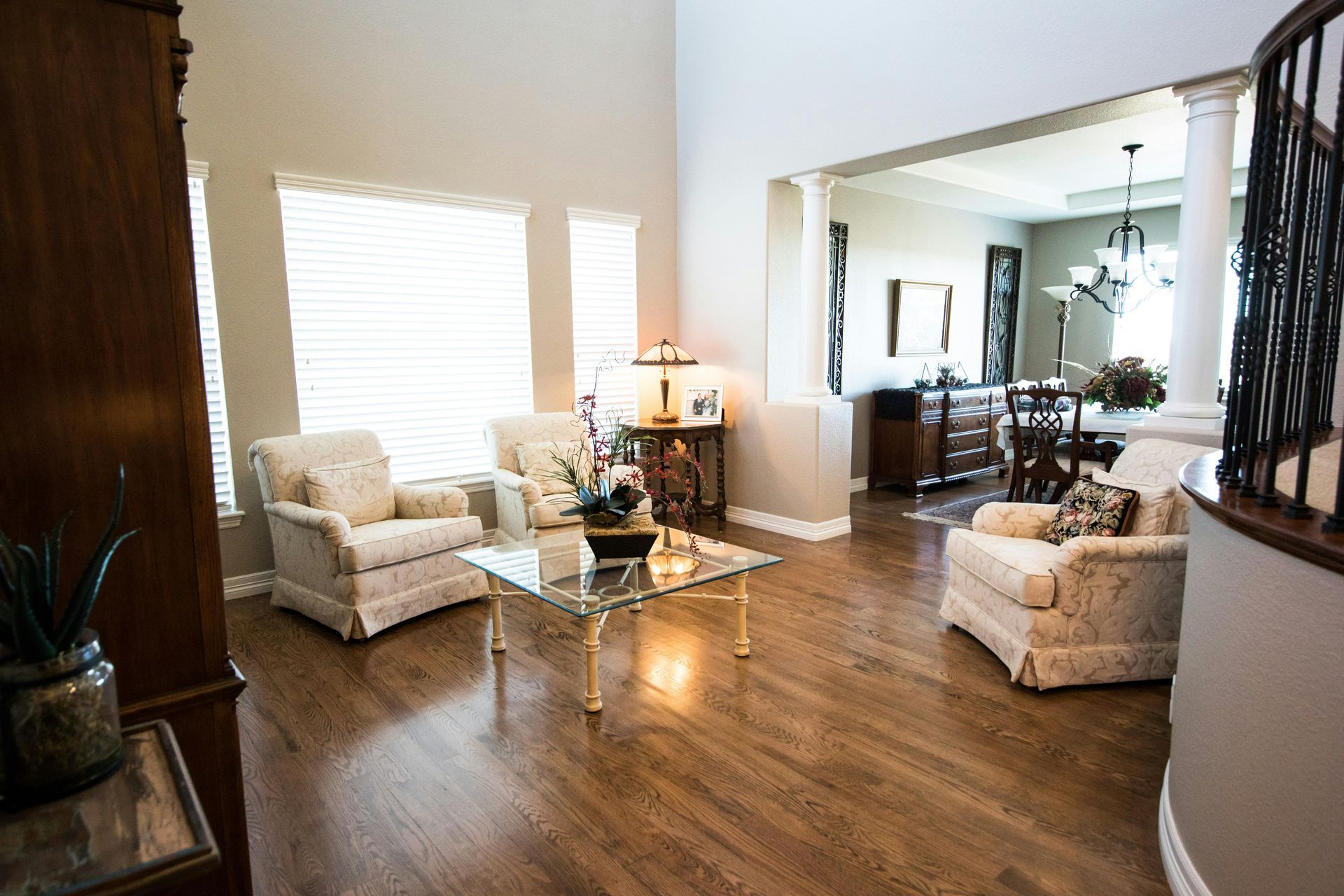 Spacious living room with armchairs, glass coffee table, and view into the dining room.