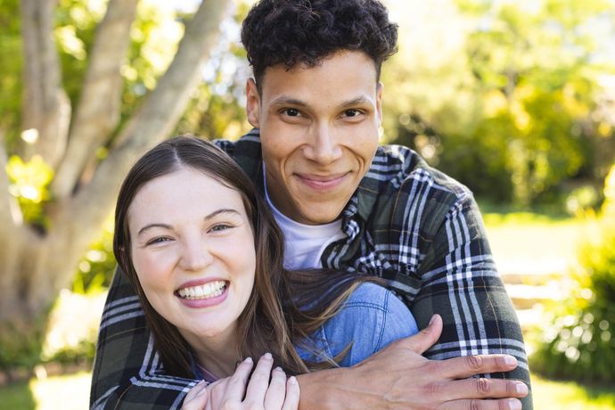 A man is carrying a woman on his back in a park.