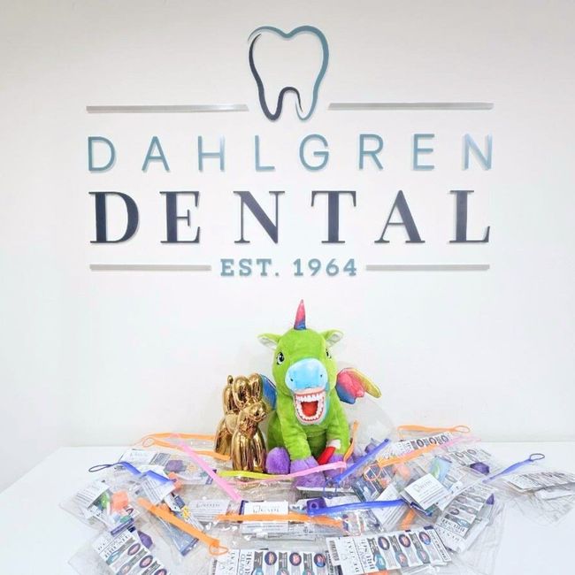 A stuffed unicorn is sitting in front of a sign for dahlgren dental