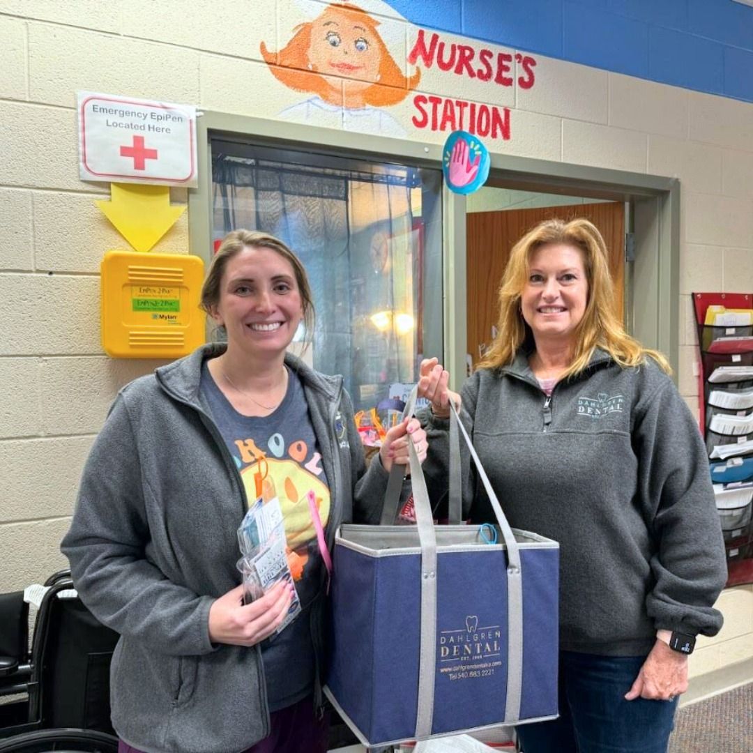 Two women are standing in front of a nurse 's station holding bags.