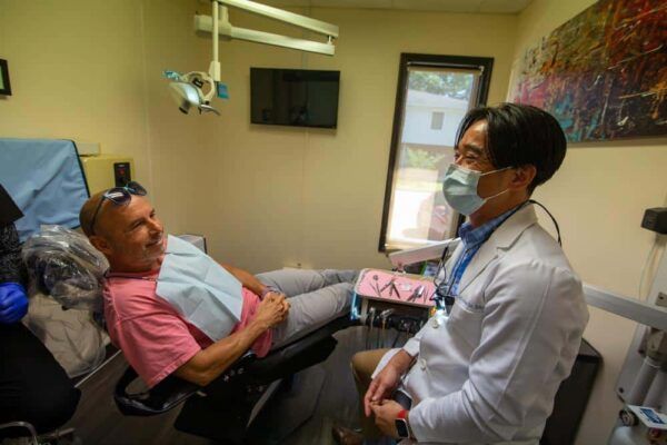 A dentist is talking to a patient in a dental chair.