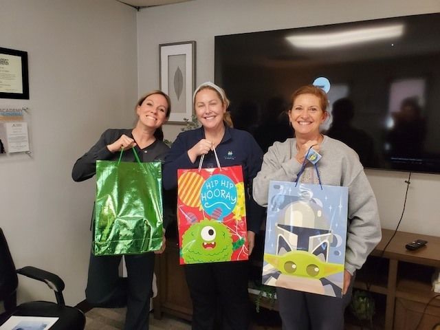 Three women holding gift bags in a room with a tv