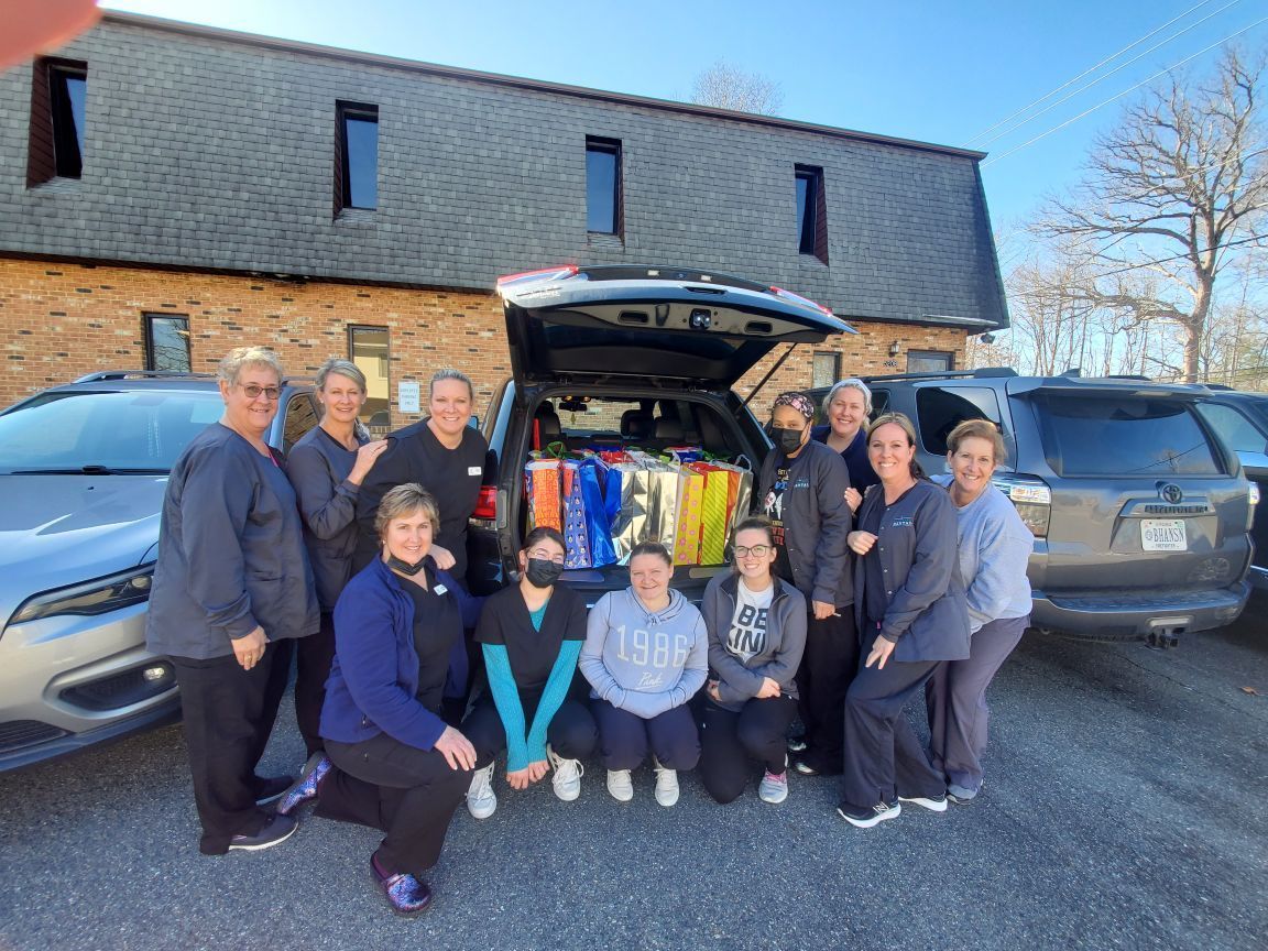 A group of people are posing for a picture in front of a car.