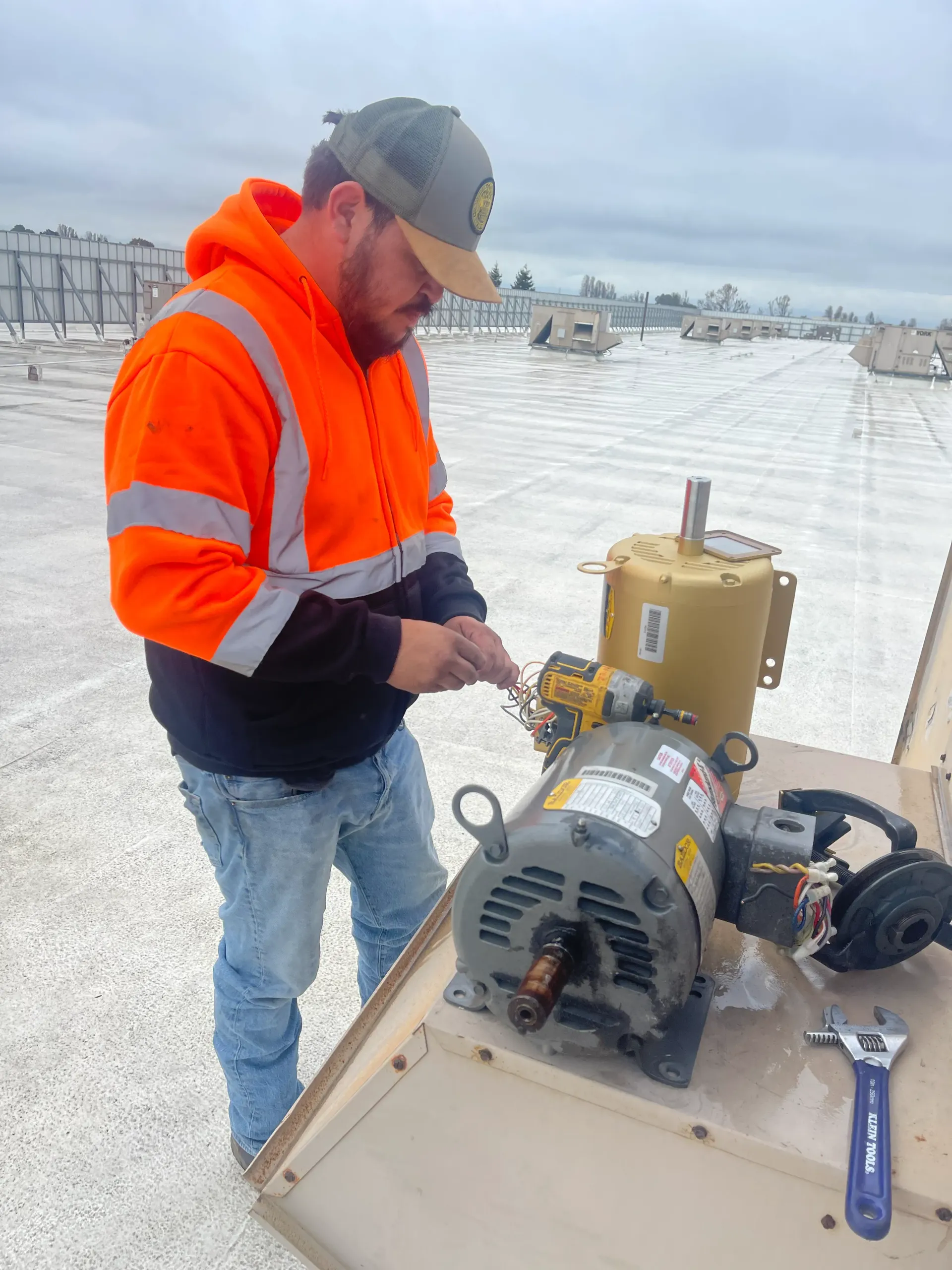A man in an orange jacket is working on a motor